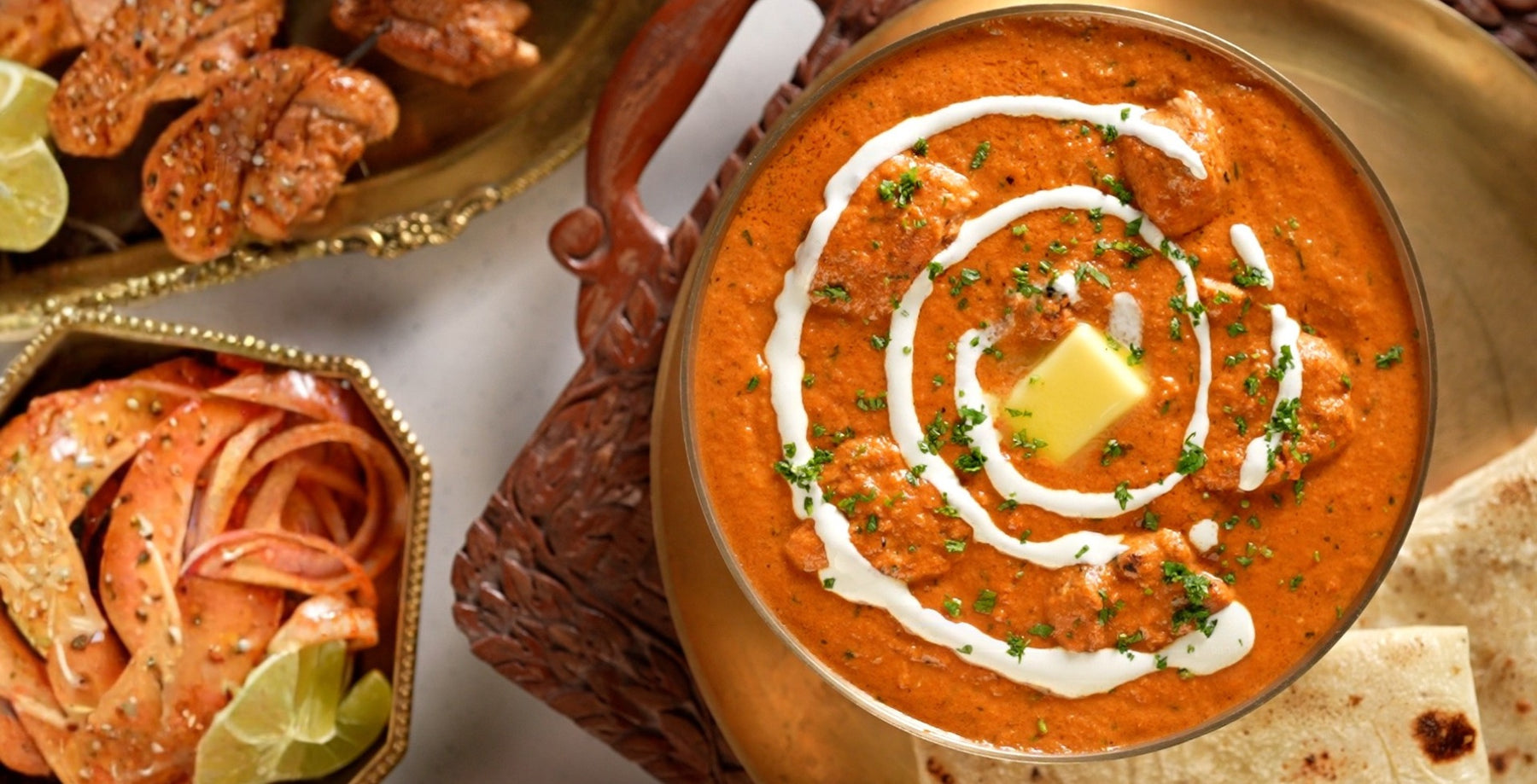 Old Delhi Butter Chicken made with Mrs Balbir Singh's award-winning spice blend, in a brass bowl with a swirl of cream and a knob of butter